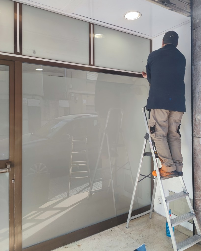 Aplicación cinta de doble cara en la escruta de aluminio antes de colocar la placa/rotulo de pvc